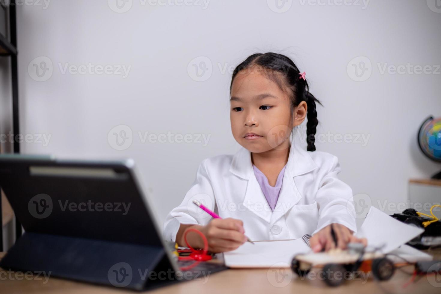 Asian students learn at home by coding robot cars and electronic board cables in STEM, STEAM, mathematics engineering science technology computer code in robotics for kids' concepts. photo