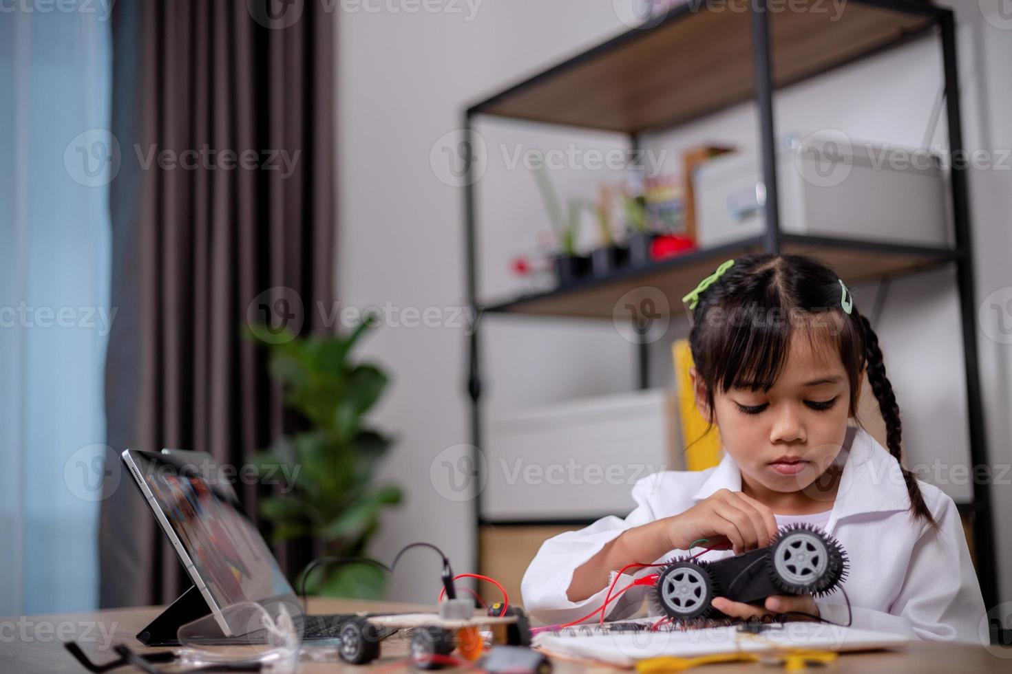 Asian students learn at home by coding robot cars and electronic board cables in STEM, STEAM, mathematics engineering science technology computer code in robotics for kids' concepts. photo