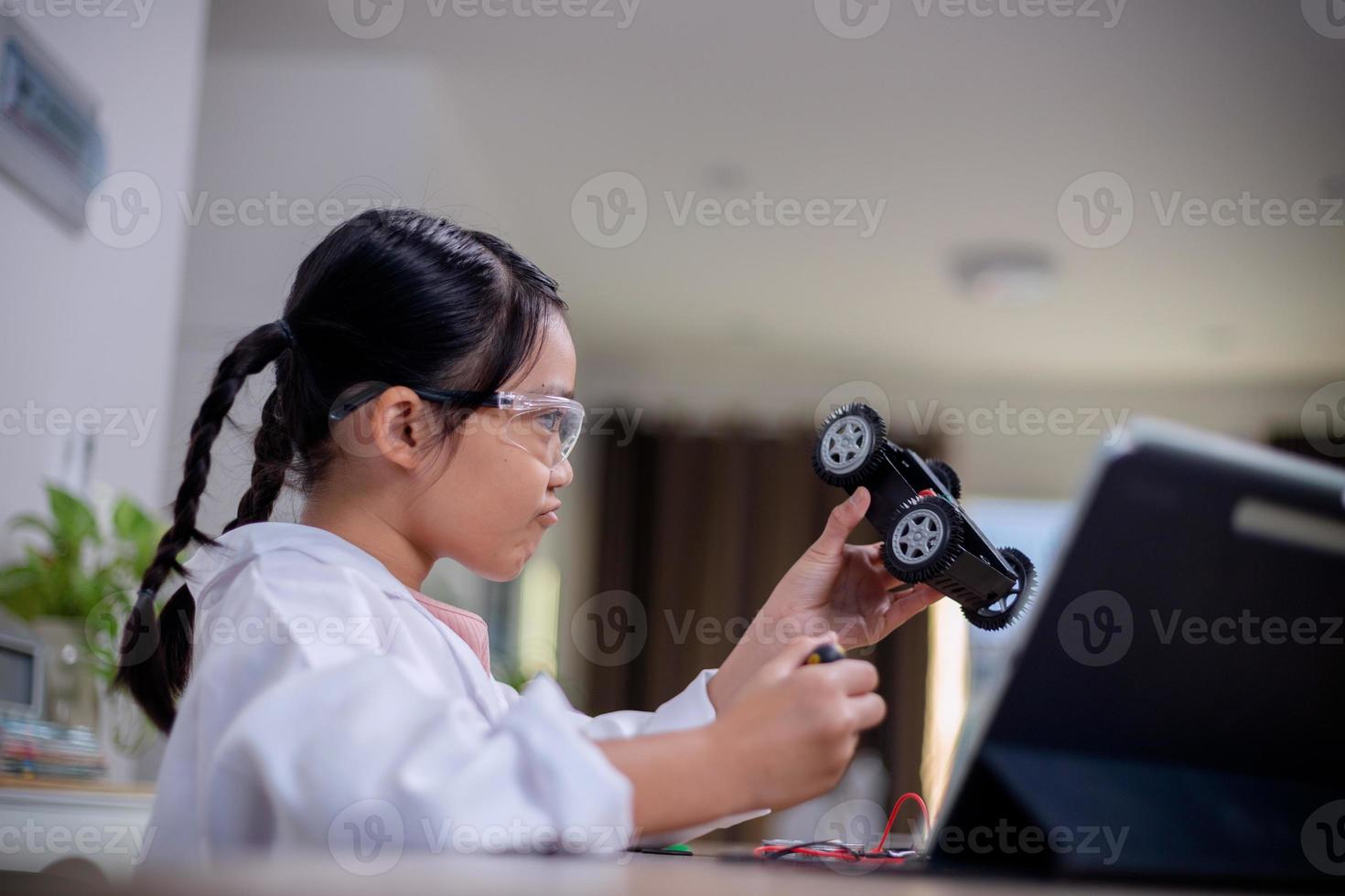 Asian students learn at home by coding robot cars and electronic board cables in STEM, STEAM, mathematics engineering science technology computer code in robotics for kids' concepts. photo