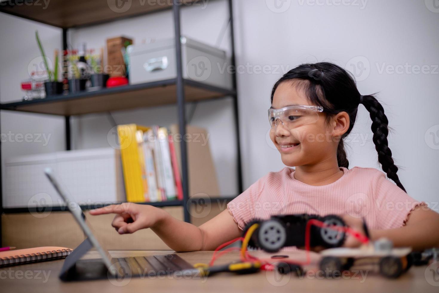 Asian students learn at home by coding robot cars and electronic board cables in STEM, STEAM, mathematics engineering science technology computer code in robotics for kids' concepts. photo