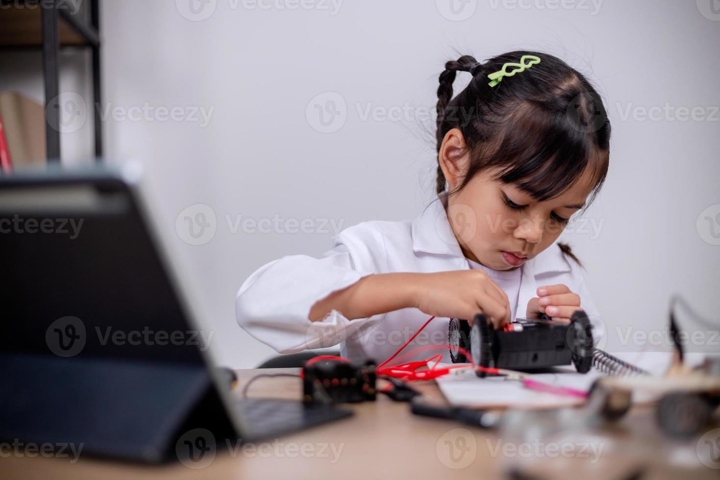 Asian students learn at home by coding robot cars and electronic board cables in STEM, STEAM, mathematics engineering science technology computer code in robotics for kids' concepts. photo