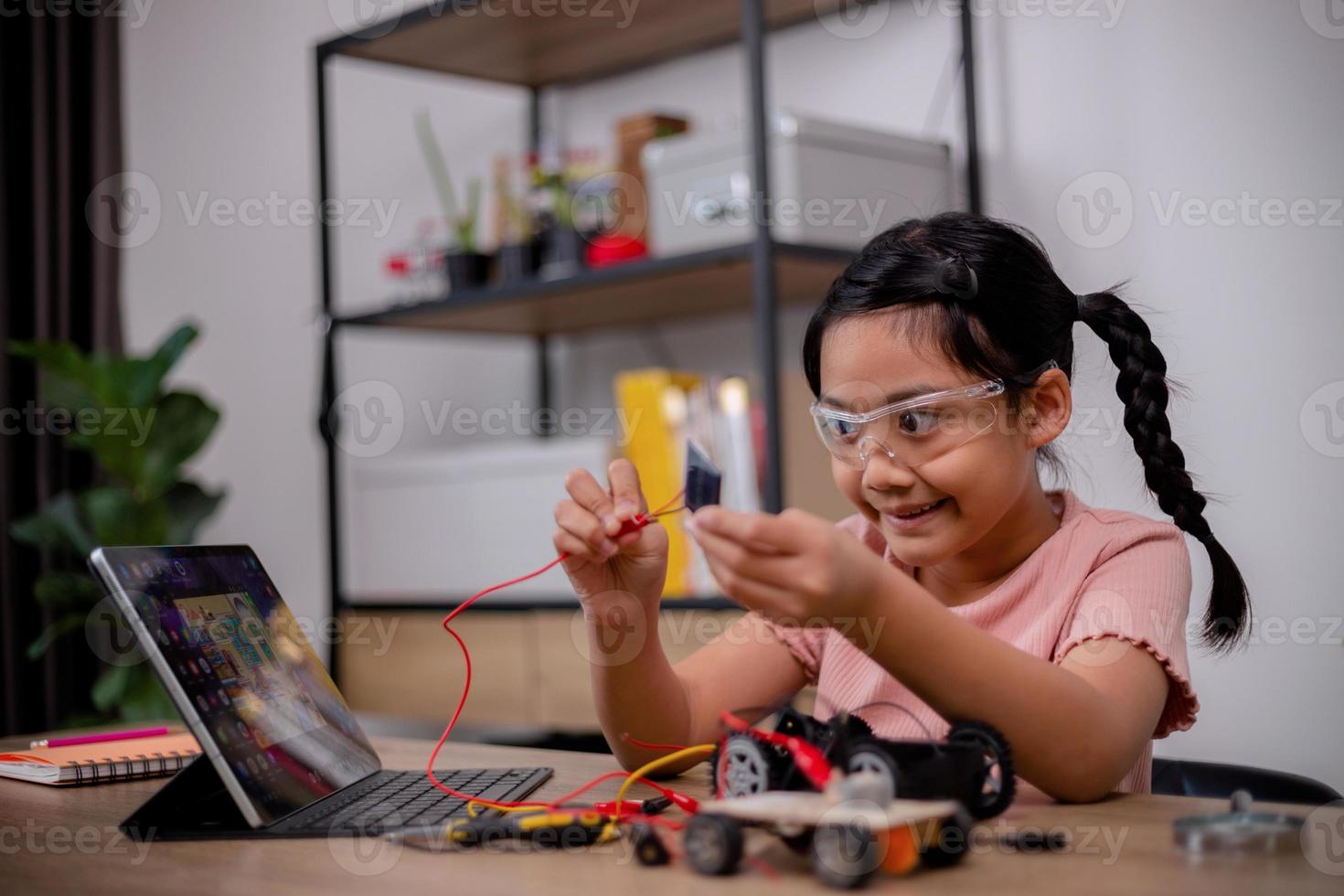 Asian students learn at home by coding robot cars and electronic board cables in STEM, STEAM, mathematics engineering science technology computer code in robotics for kids' concepts. photo