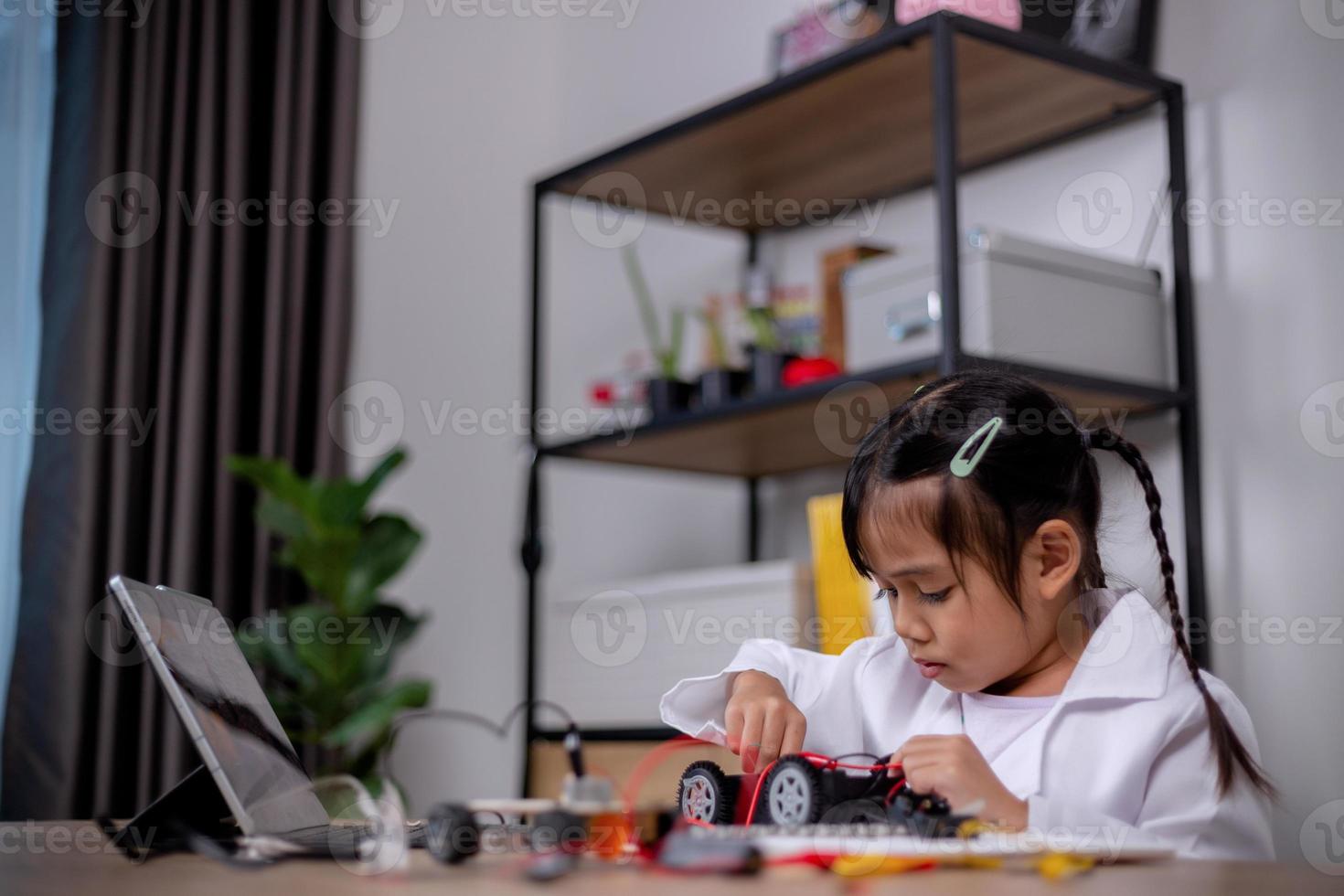 Asian students learn at home by coding robot cars and electronic board cables in STEM, STEAM, mathematics engineering science technology computer code in robotics for kids' concepts. photo
