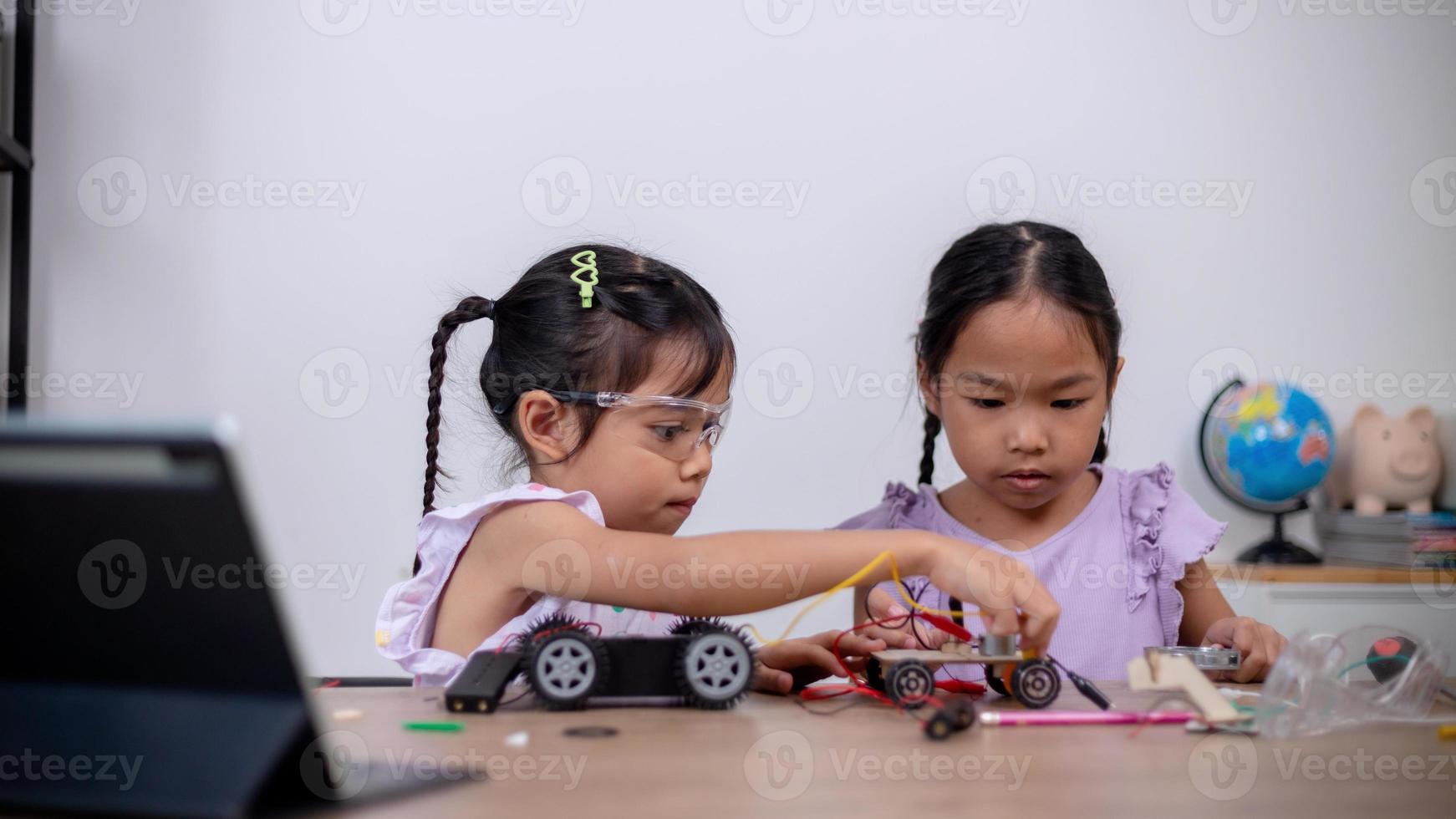 los estudiantes asiáticos aprenden en casa codificando automóviles robot y cables de placas electrónicas en tallo, vapor, ingeniería matemática, ciencia, tecnología, código informático en robótica para conceptos infantiles. foto