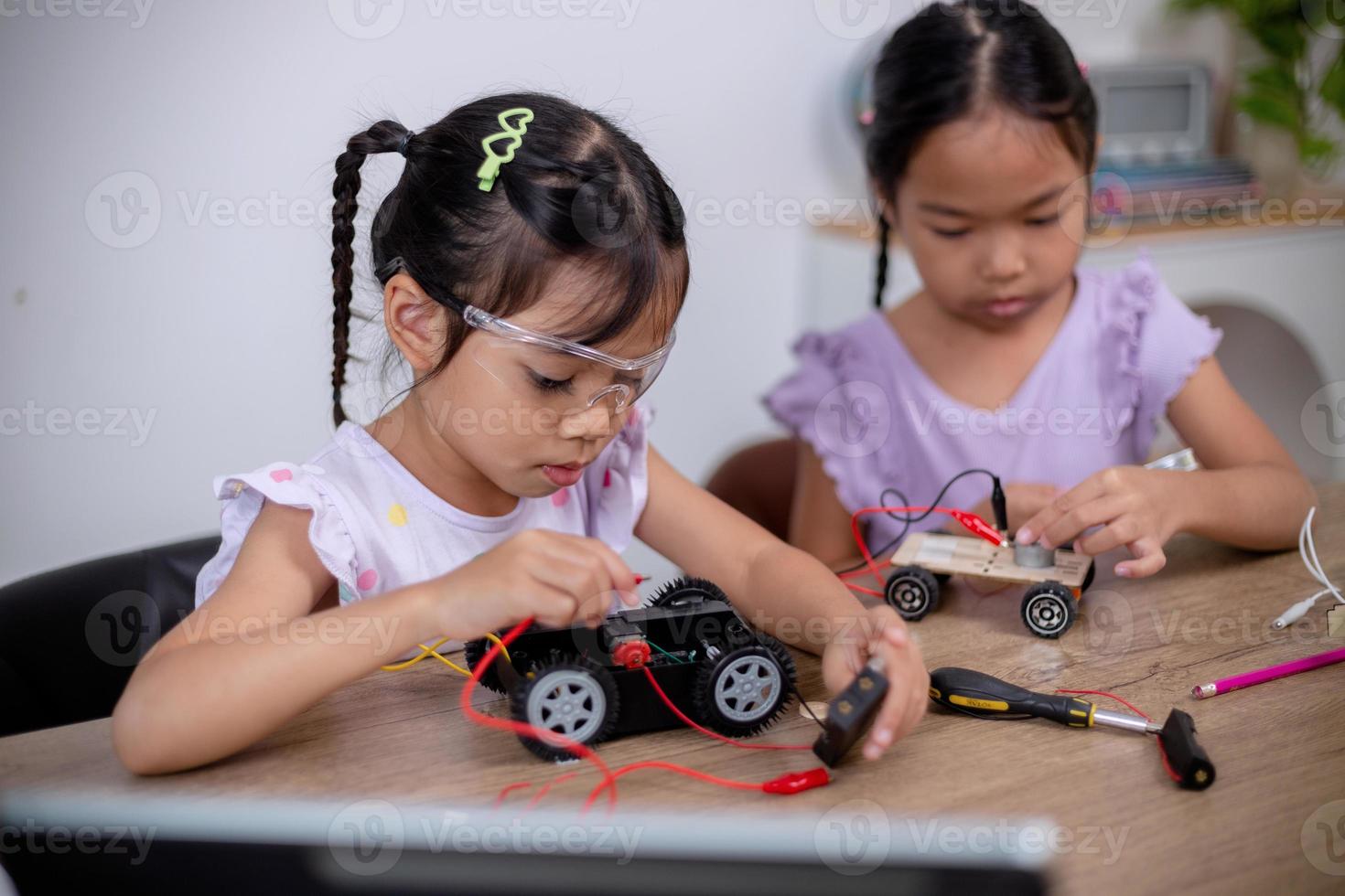 Asian students learn at home by coding robot cars and electronic board cables in STEM, STEAM, mathematics engineering science technology computer code in robotics for kids' concepts. photo
