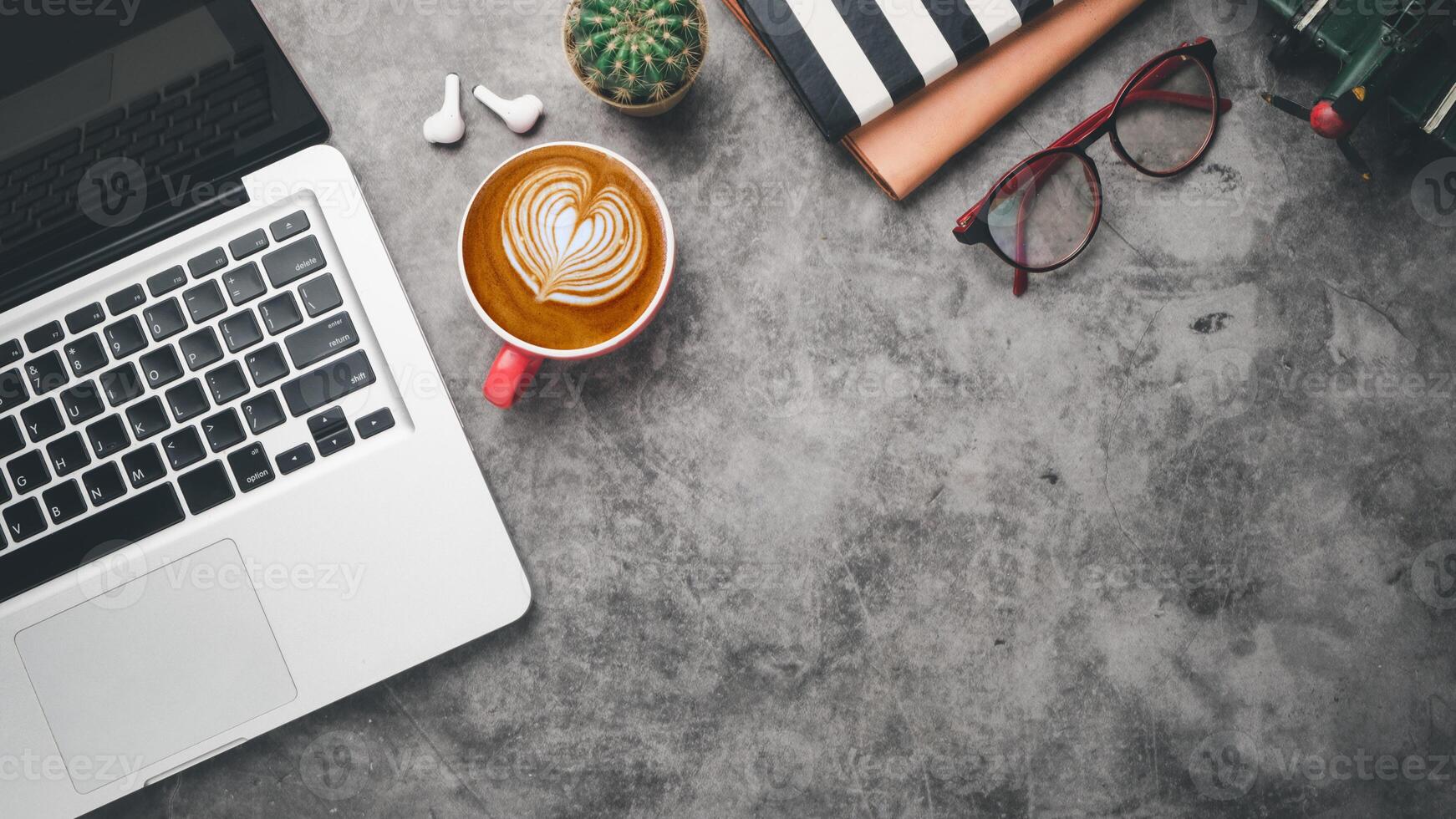 lugar de trabajo de escritorio de oficina con computadora portátil, auricular, anteojos, cuaderno y taza de café, vista superior plana con espacio para copiar. foto