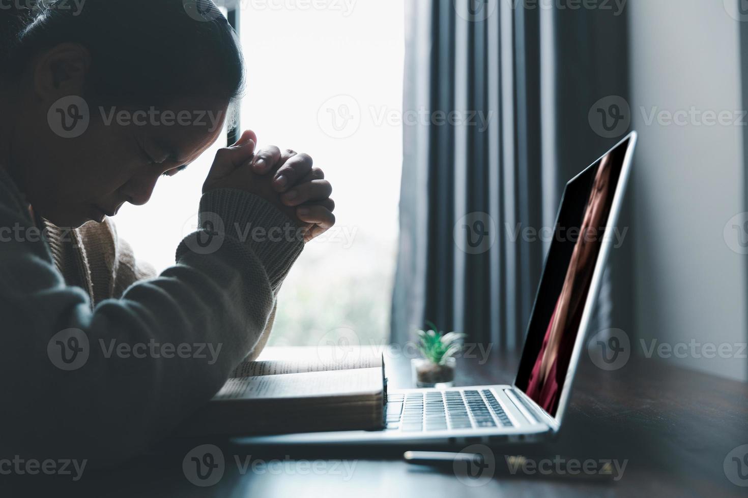 Christian online technology concept. Hands praying of christian with digital computer laptop, Online live church for sunday service. Asian catholic woman are reading Holy bible book and online study. photo