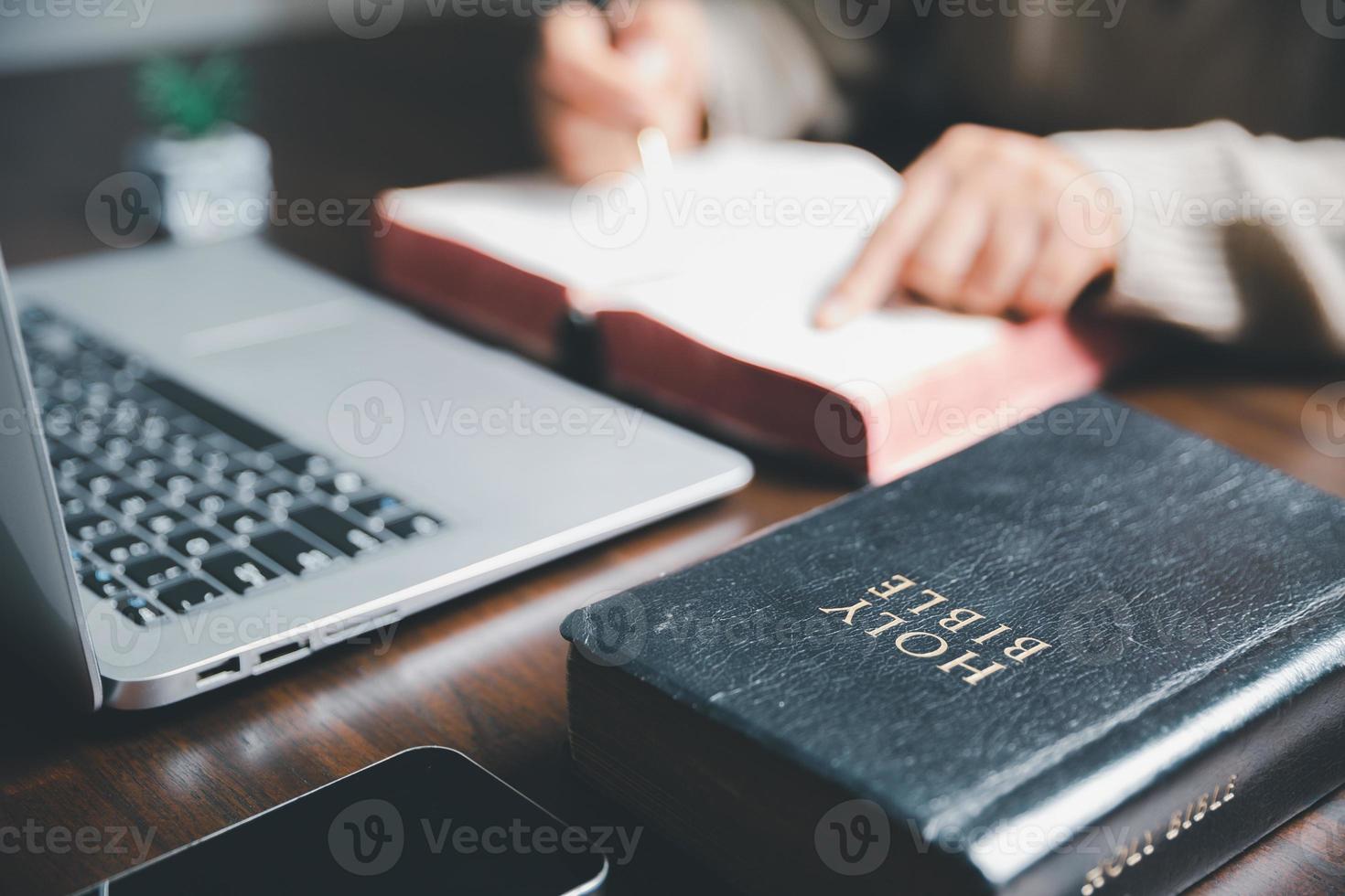 Christian online technology concept. Hands praying of christian with digital computer laptop, Online live church for sunday service. Asian catholic woman are reading Holy bible book and online study. photo