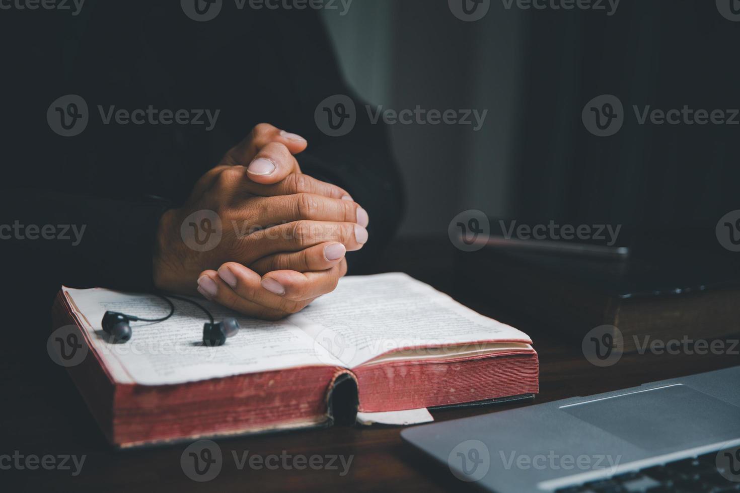 Christian online technology concept. Hands praying of christian with digital computer laptop, Online live church for sunday service. Asian catholic man are reading Holy bible book and online study. photo