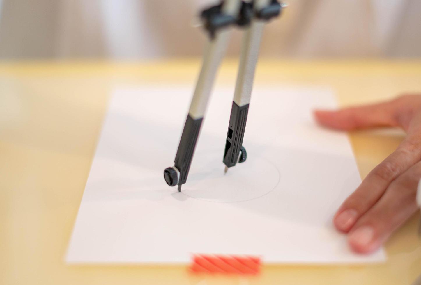mano femenina usando un círculo de medida preparándose para dibujar y dibujar en el papel blanco vacío. foto