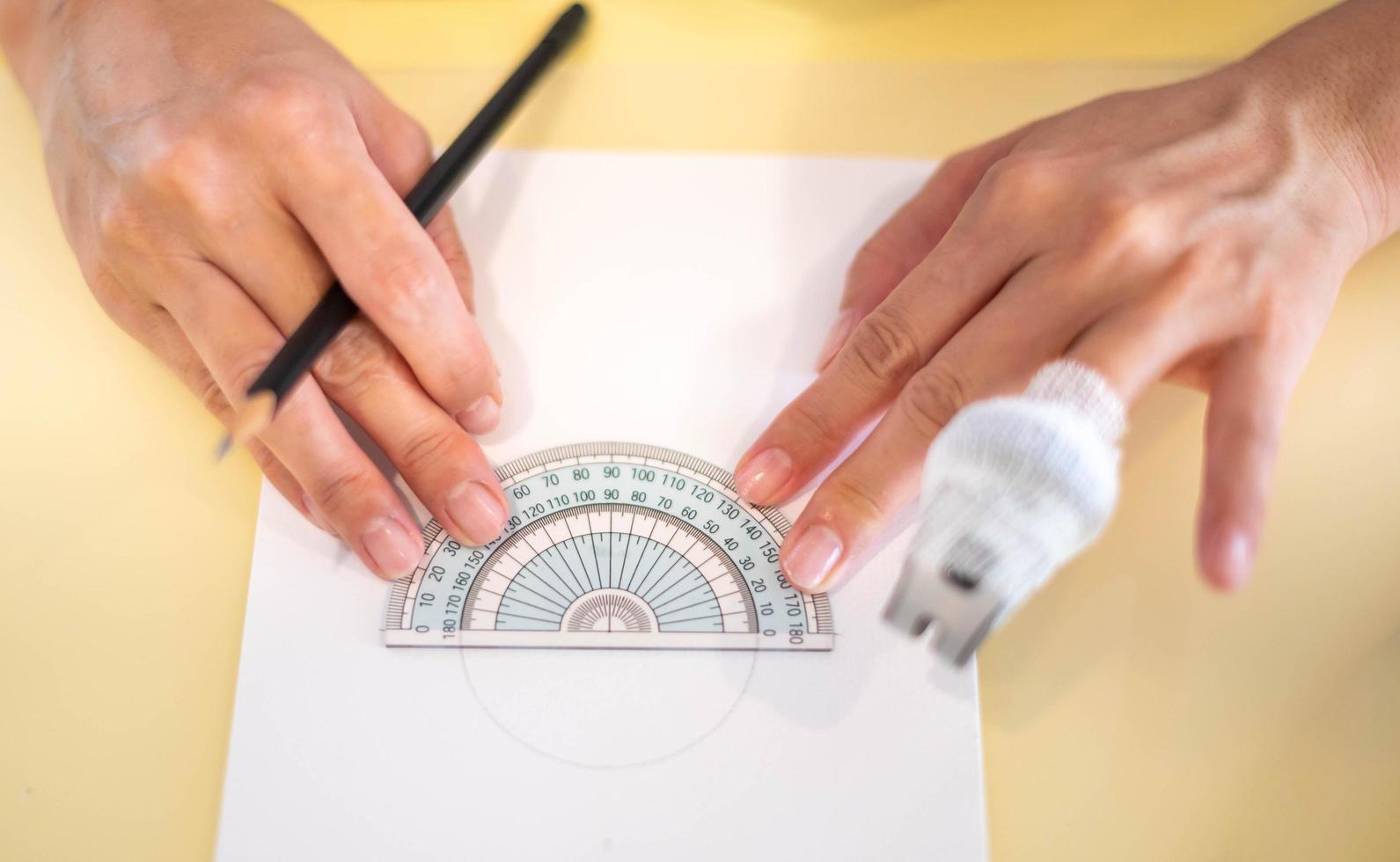 Female hand using a measure circle ruler with a wood pencil preparing to draw and sketch on the empty white paper. photo
