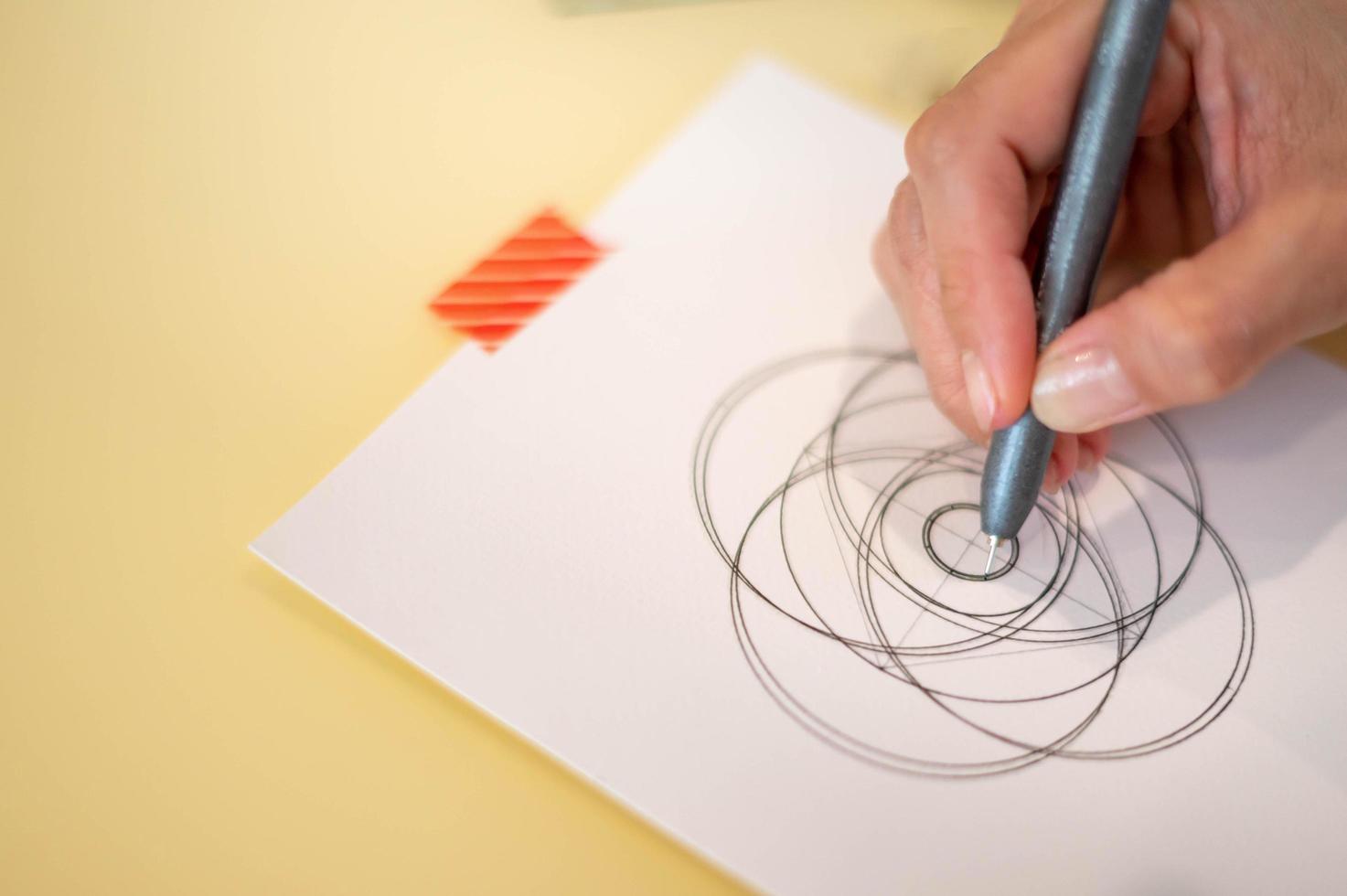 Female hand using a black magic pen preparing to draw and sketch the mandala concept on the empty white paper. photo