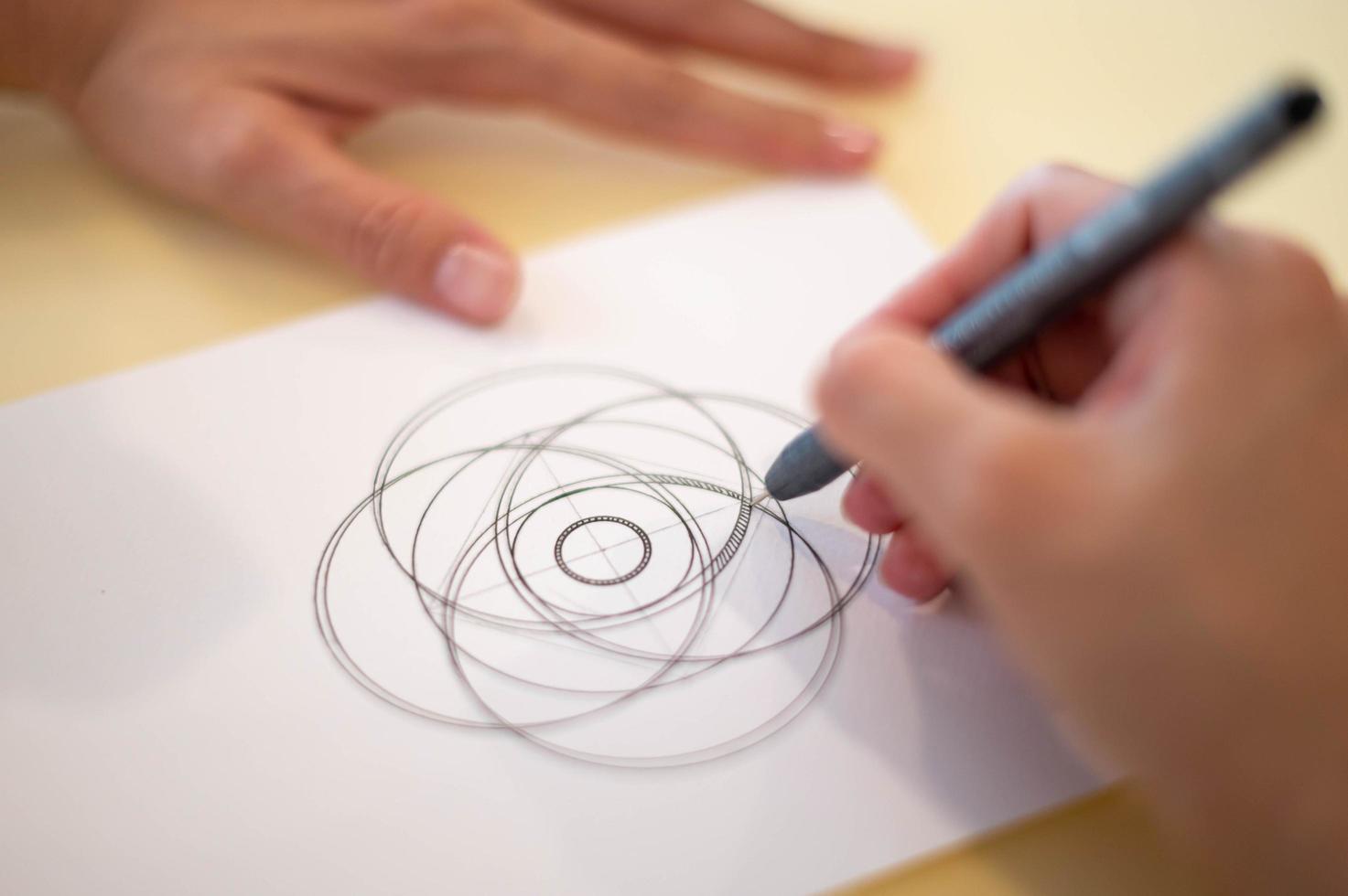 Female hand using a black magic pen preparing to draw and sketch the mandala concept on the empty white paper. photo