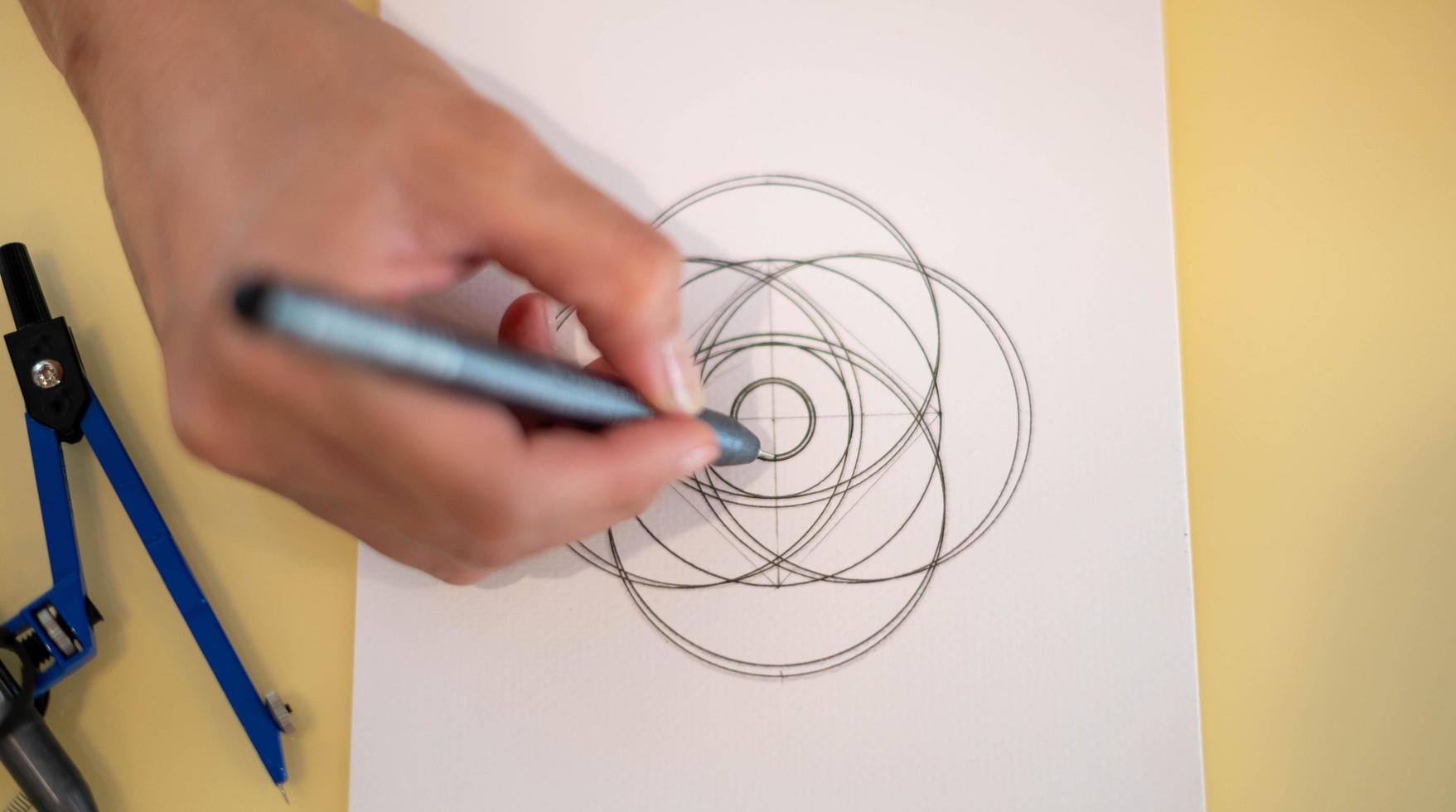 Female hand using a black magic pen preparing to draw and sketch the mandala concept on the empty white paper. photo