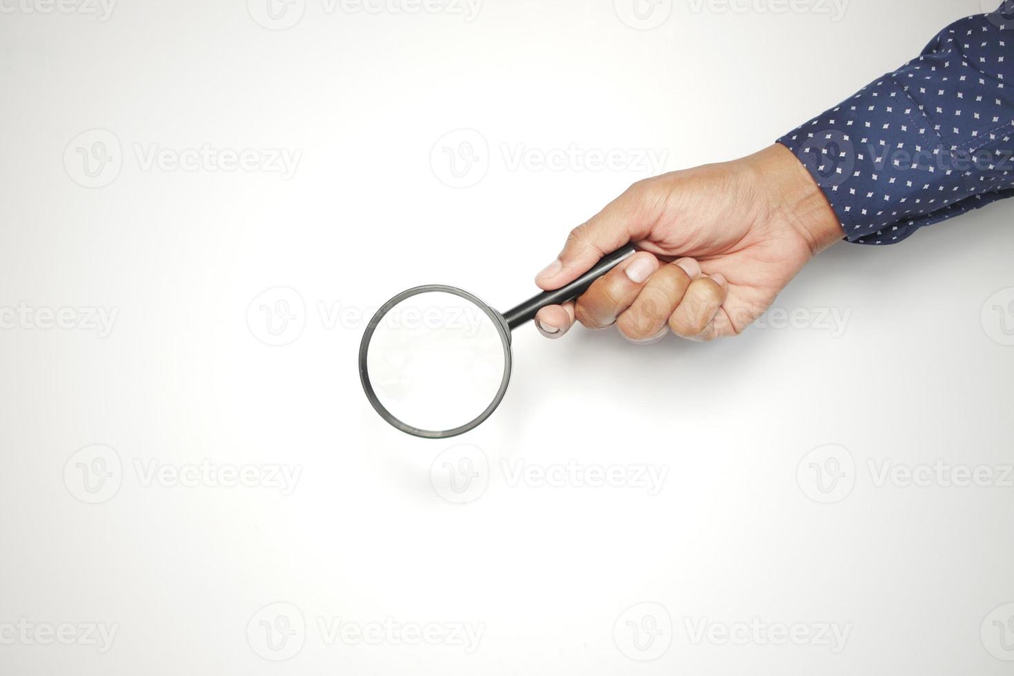 hand holding magnifying glass against white photo