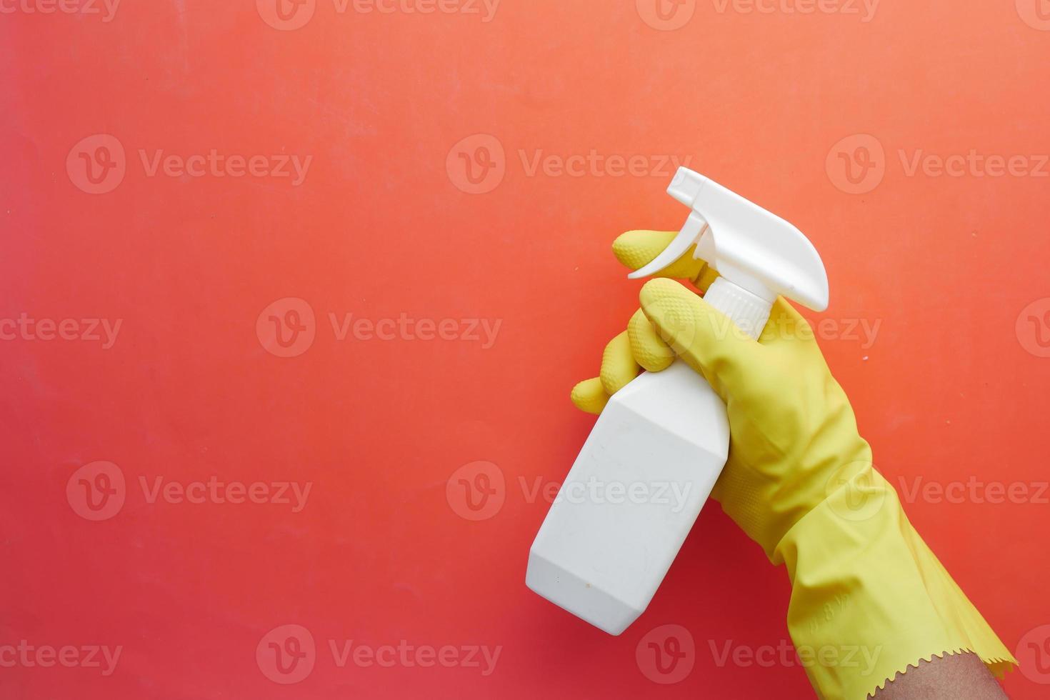 Mano en guantes de goma azul sosteniendo una botella de spray con espacio de copia foto