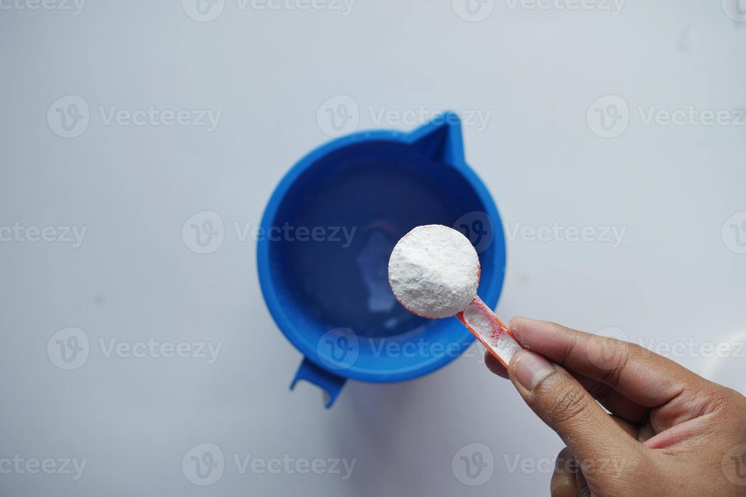 Washing powder in plastic spoon on black background top view. photo