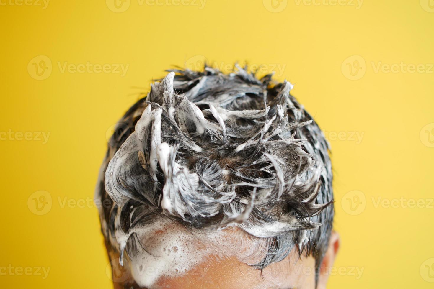 young men washes h his hair with shampoo . photo