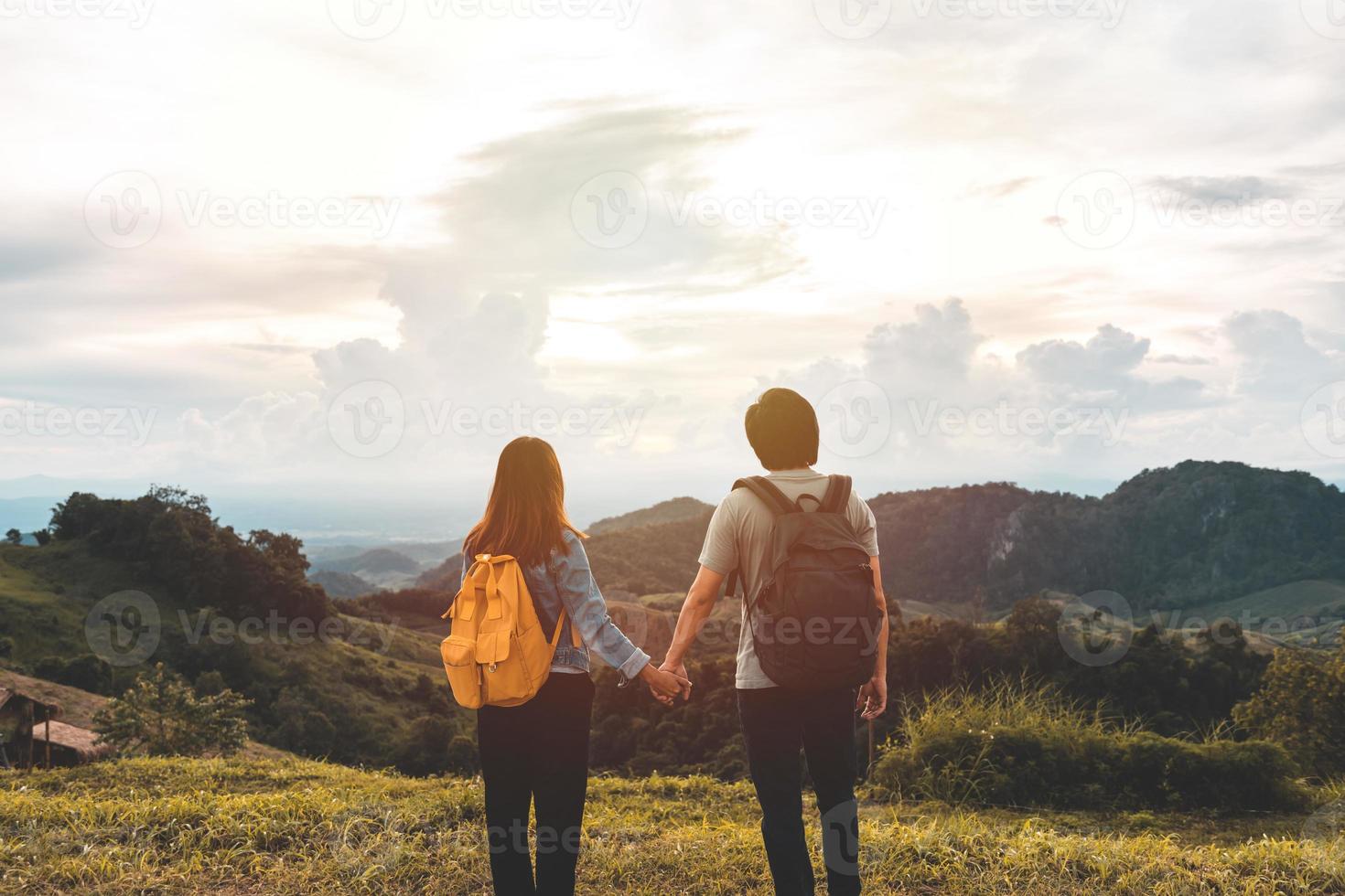 Happy young couple traveler relaxing and looking at the beautiful sunset on the top of mountain photo