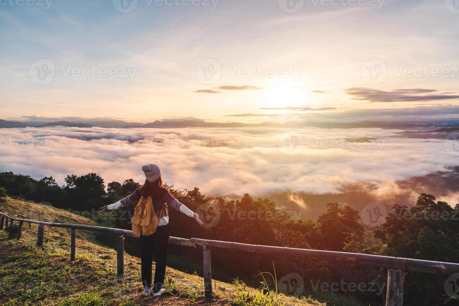 Young woman travelers looking at the sunrise and the sea of mist on the mountain in the morning, Travel lifestyle concept photo