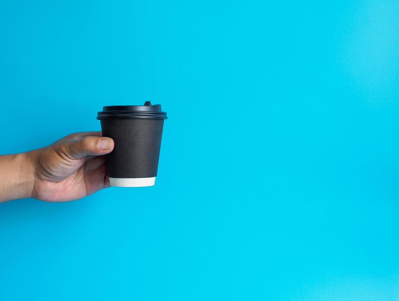 Man hand holding a white coffee cup, filled with hot black coffee americano, no sugar no milk, ready to drink, refreshing. aroma awake fresh to work placed on a blue isolated background photo