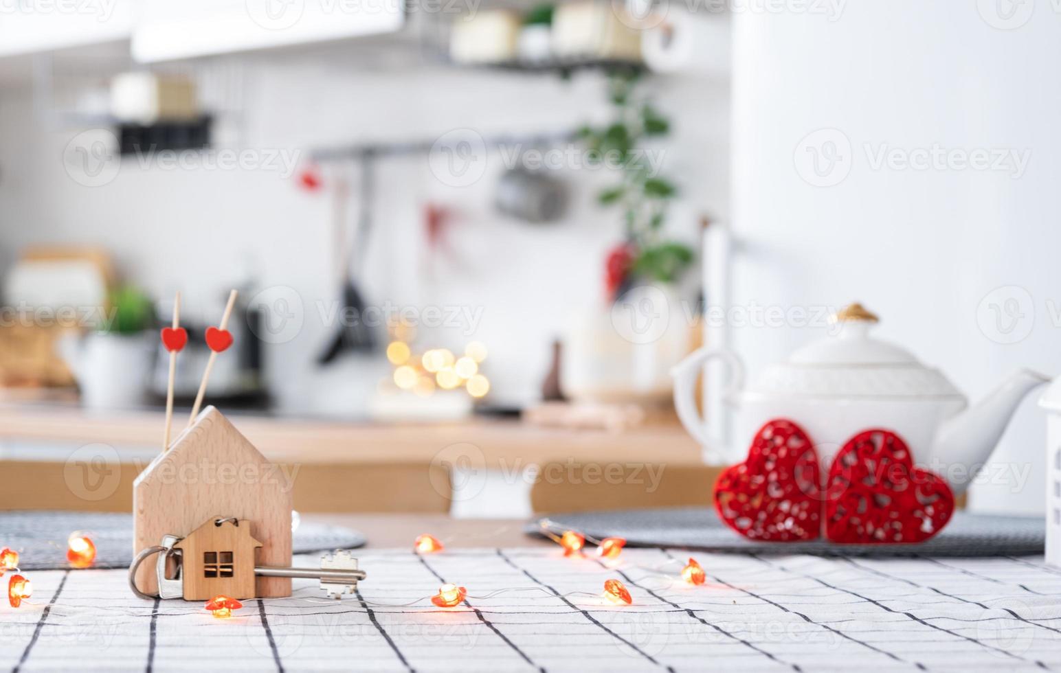 Key to house of cozy home with Valentine decor on table of kitchen. Gift for valentines day, family love nest. Building, design, project, moving to new house, mortgage, rent and purchase real estate photo