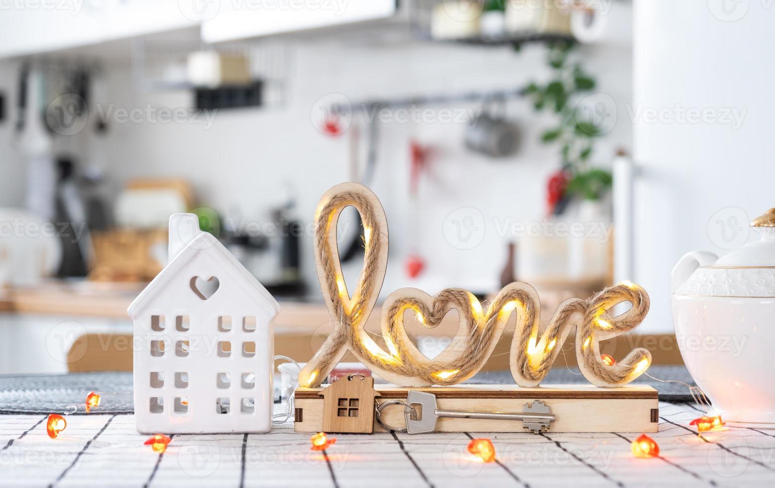 Key to house of cozy home with Valentine decor on table of kitchen. Gift for valentines day, family love nest. Building, design, project, moving to new house, mortgage, rent and purchase real estate photo