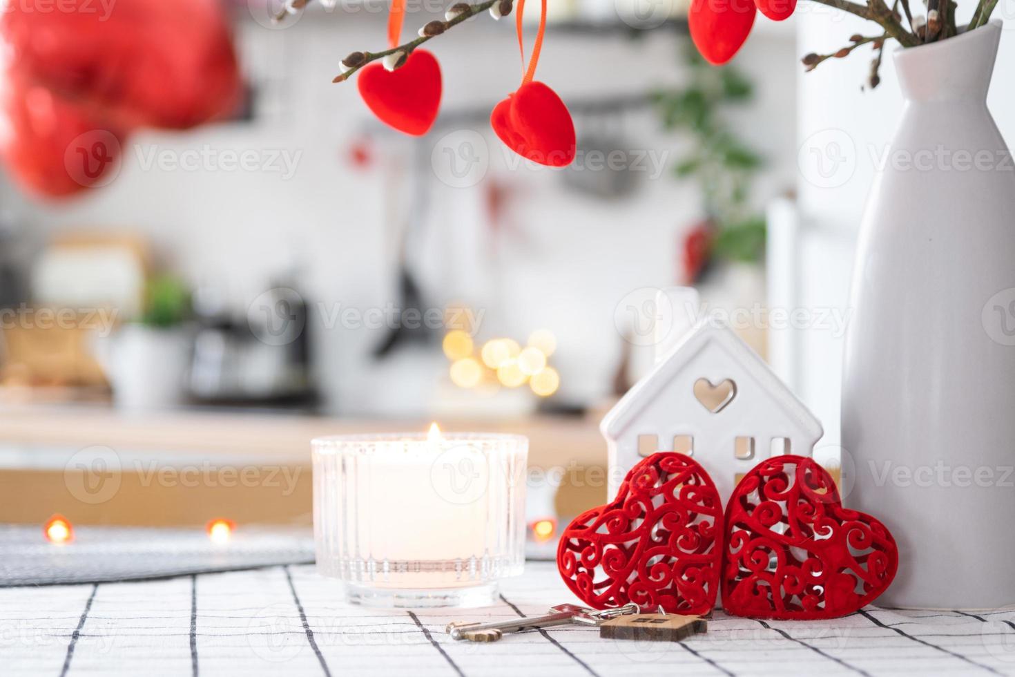 Key to house of cozy home with Valentine decor on table of kitchen. Gift for valentines day, family love nest. Building, design, project, moving to new house, mortgage, rent and purchase real estate photo