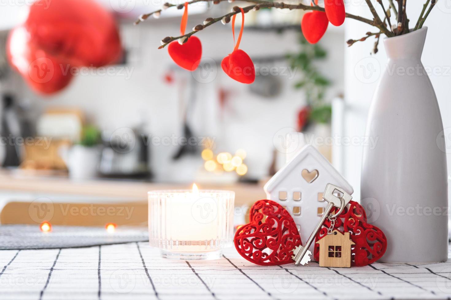 Key to house of cozy home with Valentine decor on table of kitchen. Gift for valentines day, family love nest. Building, design, project, moving to new house, mortgage, rent and purchase real estate photo