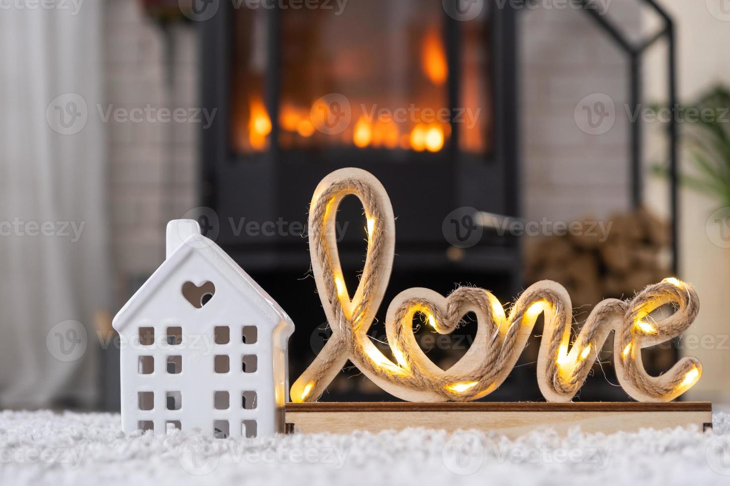 Key to house with keychain against background of fireplace stove with fire and firewood in Valentine decor, love home. Moving to new house, mortgage, rent and purchase real estate photo