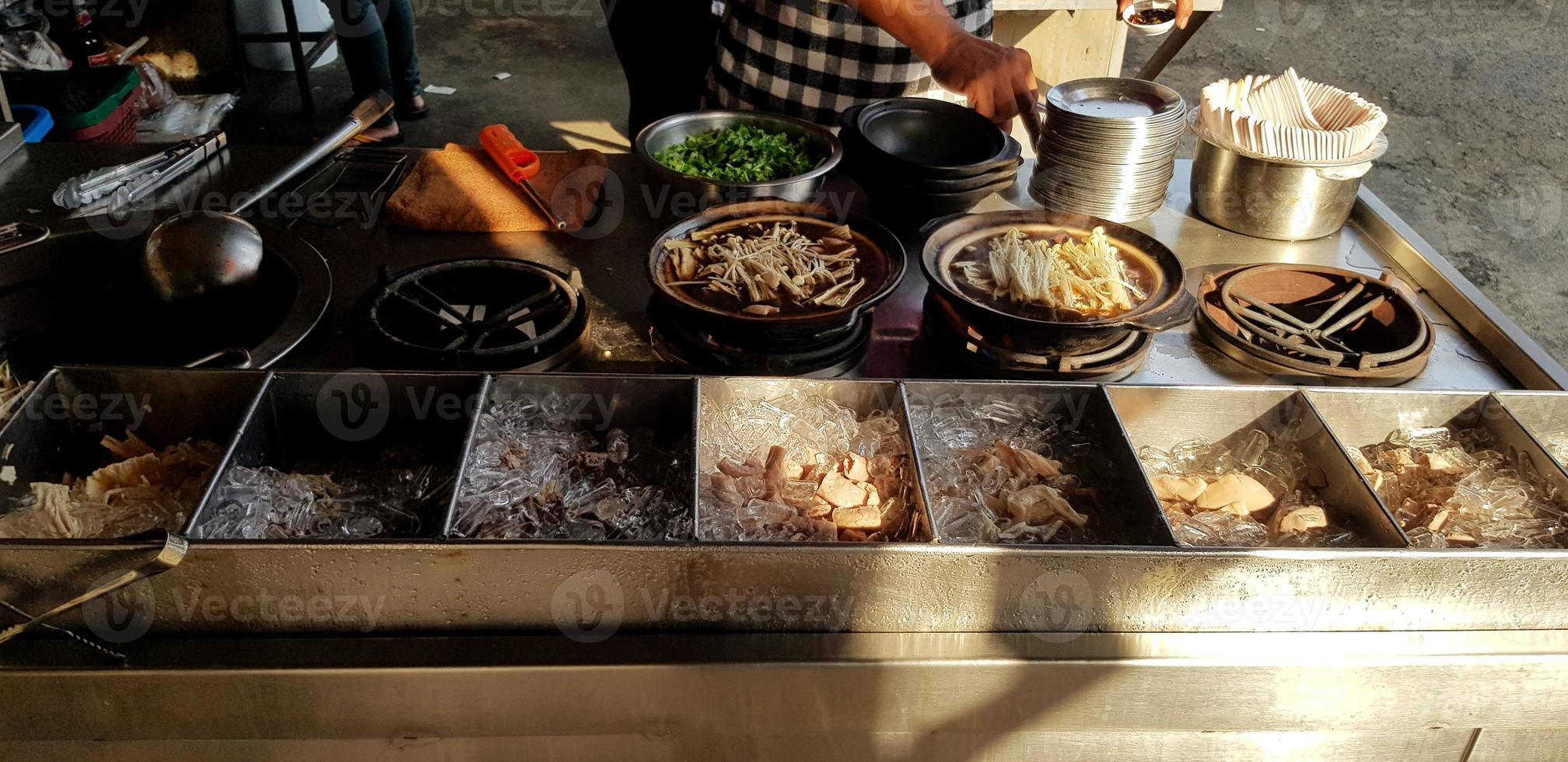 Man's hand cooking hot Bak kut teh on pot for sale with sunlight in the morning on food street market - Kitchen , Preparation and Service concept photo