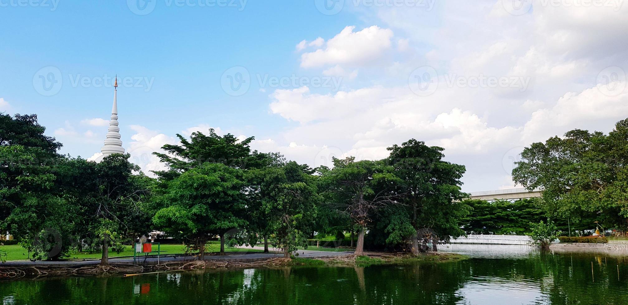 Beautiful green park with lake, tree, white pagoda, clouds and blue sky background. Beautiful in Nature, Relaxing place and Environment in urban city concept photo