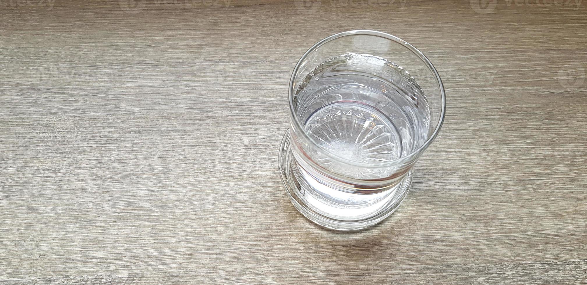 Top view or Flat lay Glass of cold water putting on light brown or gray wooden table for background with copy space. Refreshment, Drink, Object, Clearly and Shinning concept photo