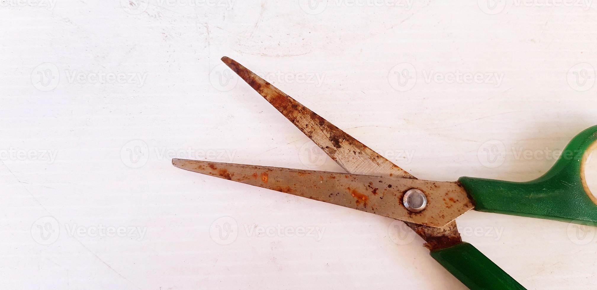 Old green rusty scissor putting and isolated on white paper with left copy space. Vintage or Single object concept photo