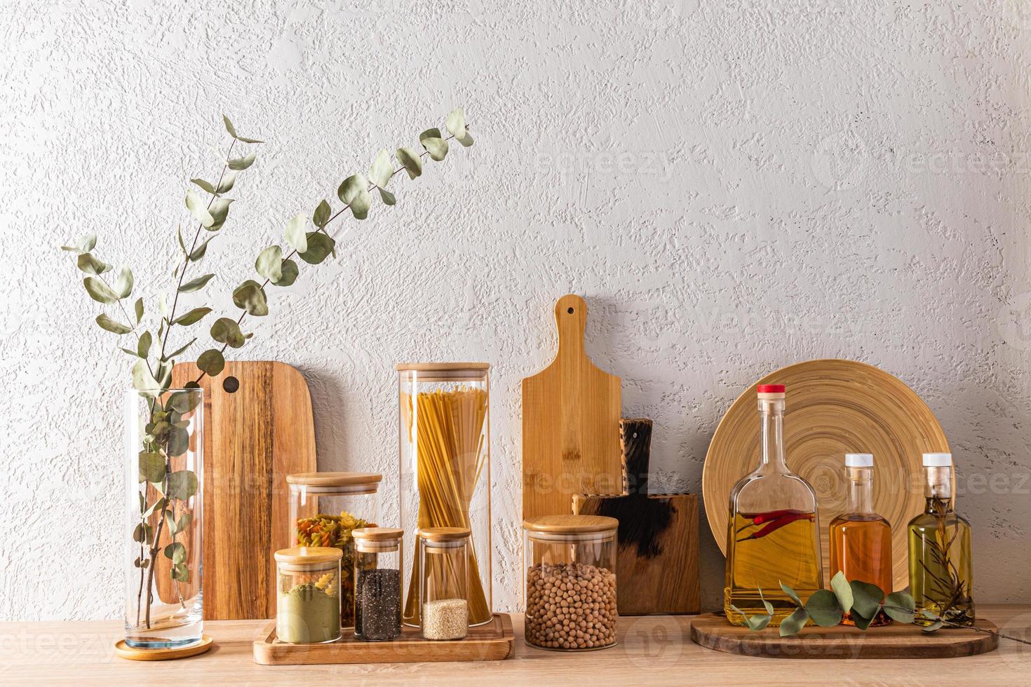 the concept of storing food in the kitchen. bulk products in glass jars and different types of oil in bottles. front view. grey cement wall. photo