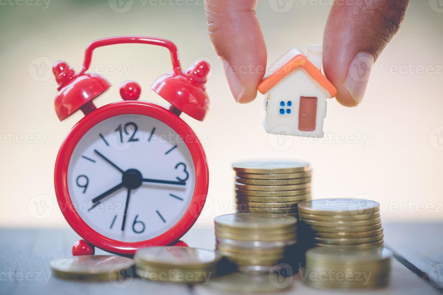 Woman's hand putting house model on coins stack. Concept for property ladder, planning savings money of coins to buy a home concept property mortgage and investment for a house. photo