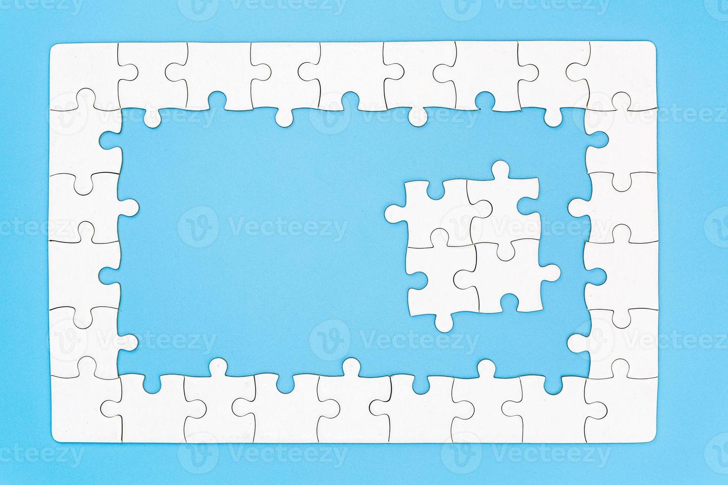 Unfinished white jigsaw puzzle pieces on blue background, The last piece of jigsaw puzzle, Copy space. photo