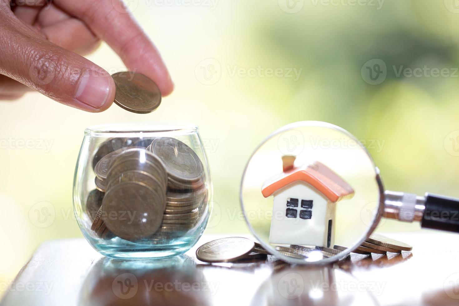 Hand putting money coin stack with small house, purchase of habitation, buy a house,Risk, Assets, Property Investment, Saving money for property investment concept. photo