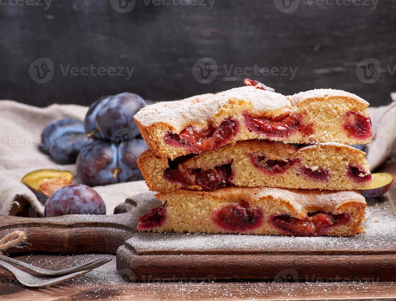 stack of triangular slices of sponge cake with blue plums photo