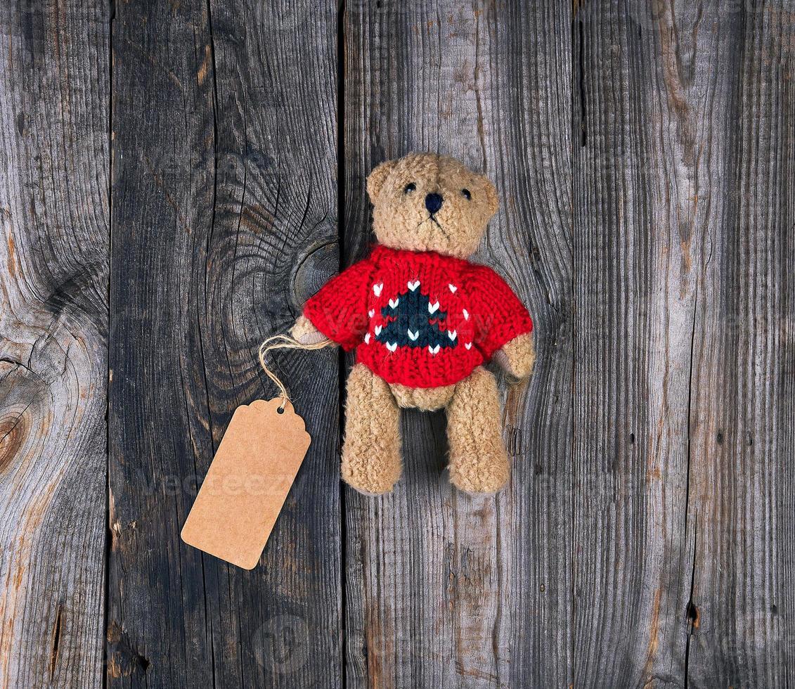 pequeño oso de peluche viejo marrón con una etiqueta de papel en blanco foto