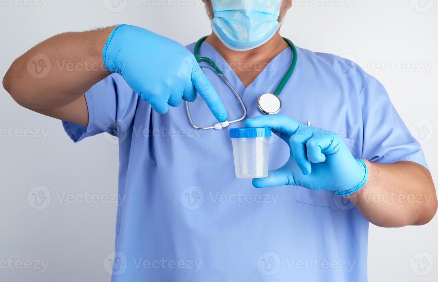 doctor in blue uniform and latex gloves is holding an empty plastic container for taking urine samples photo