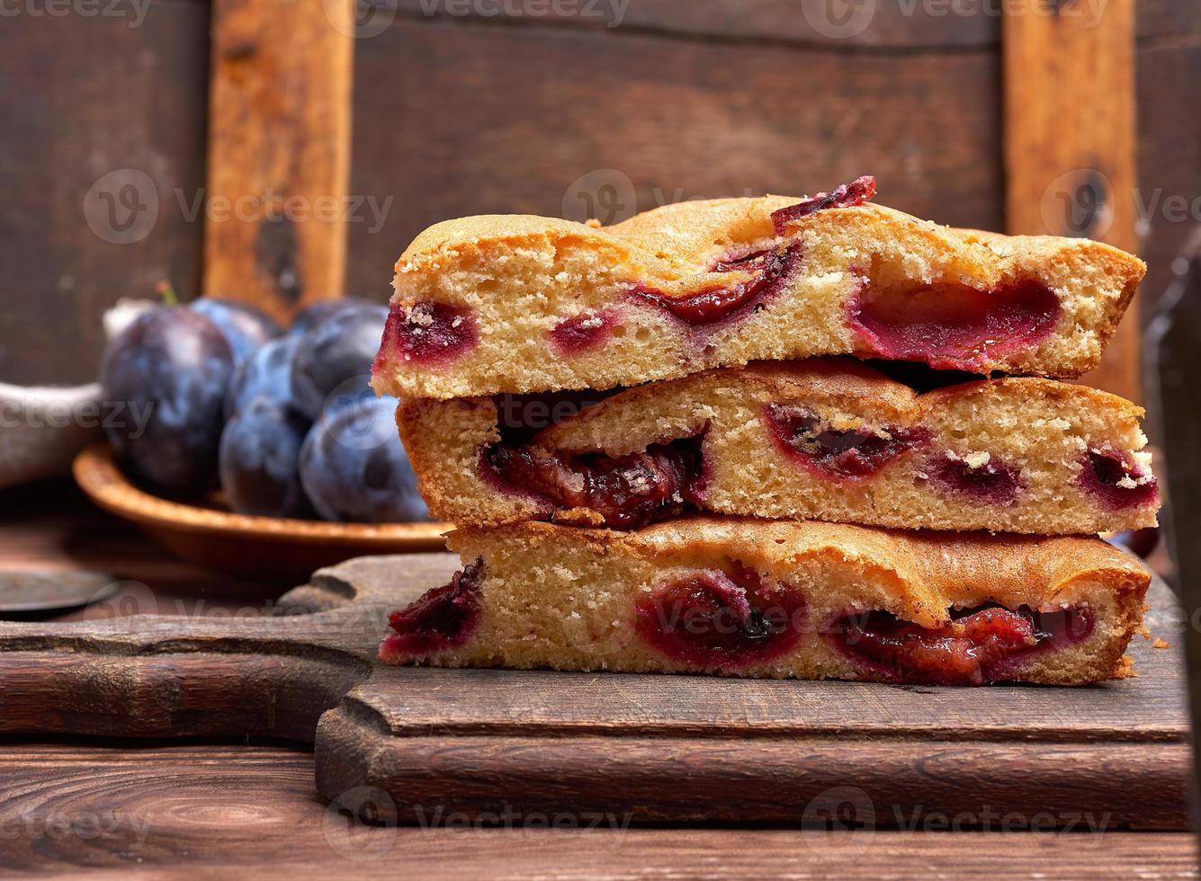 stack of triangular slices of sponge cake with blue plums photo
