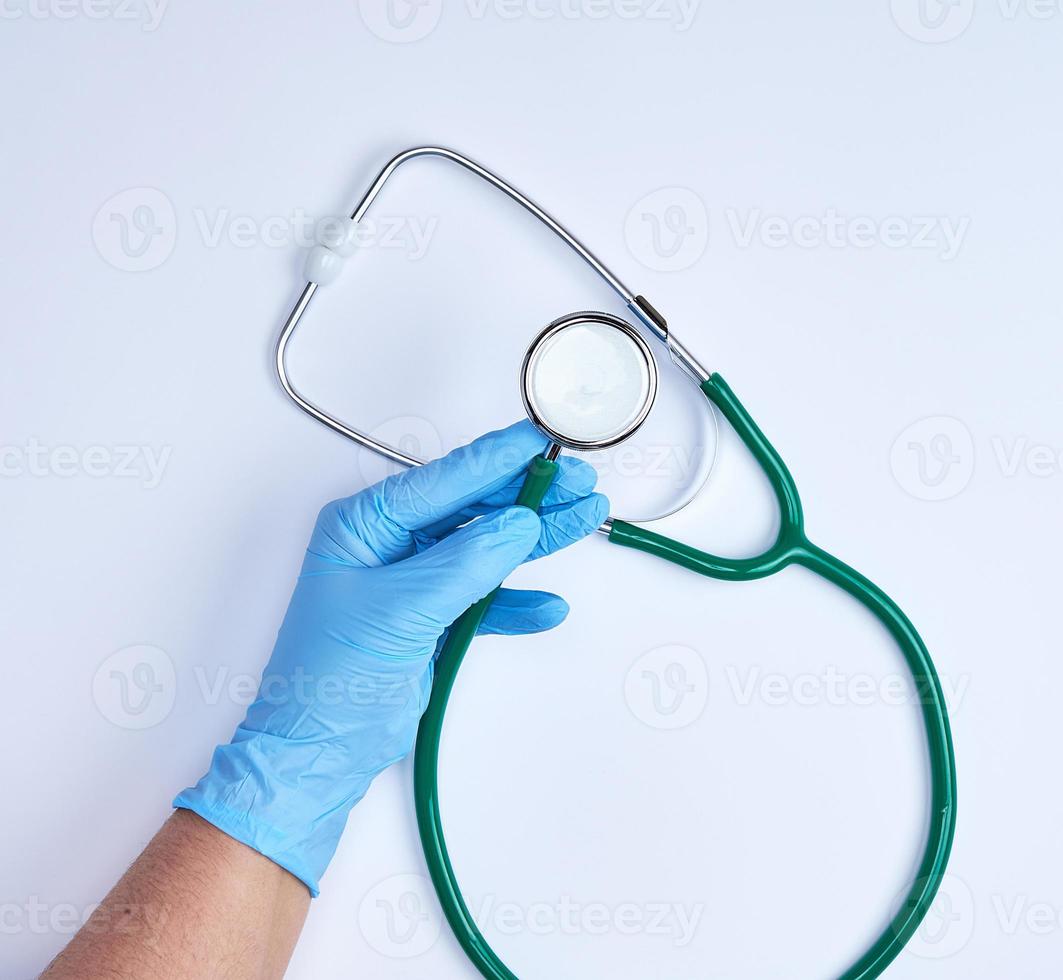 green medical stethoscope in human hand photo