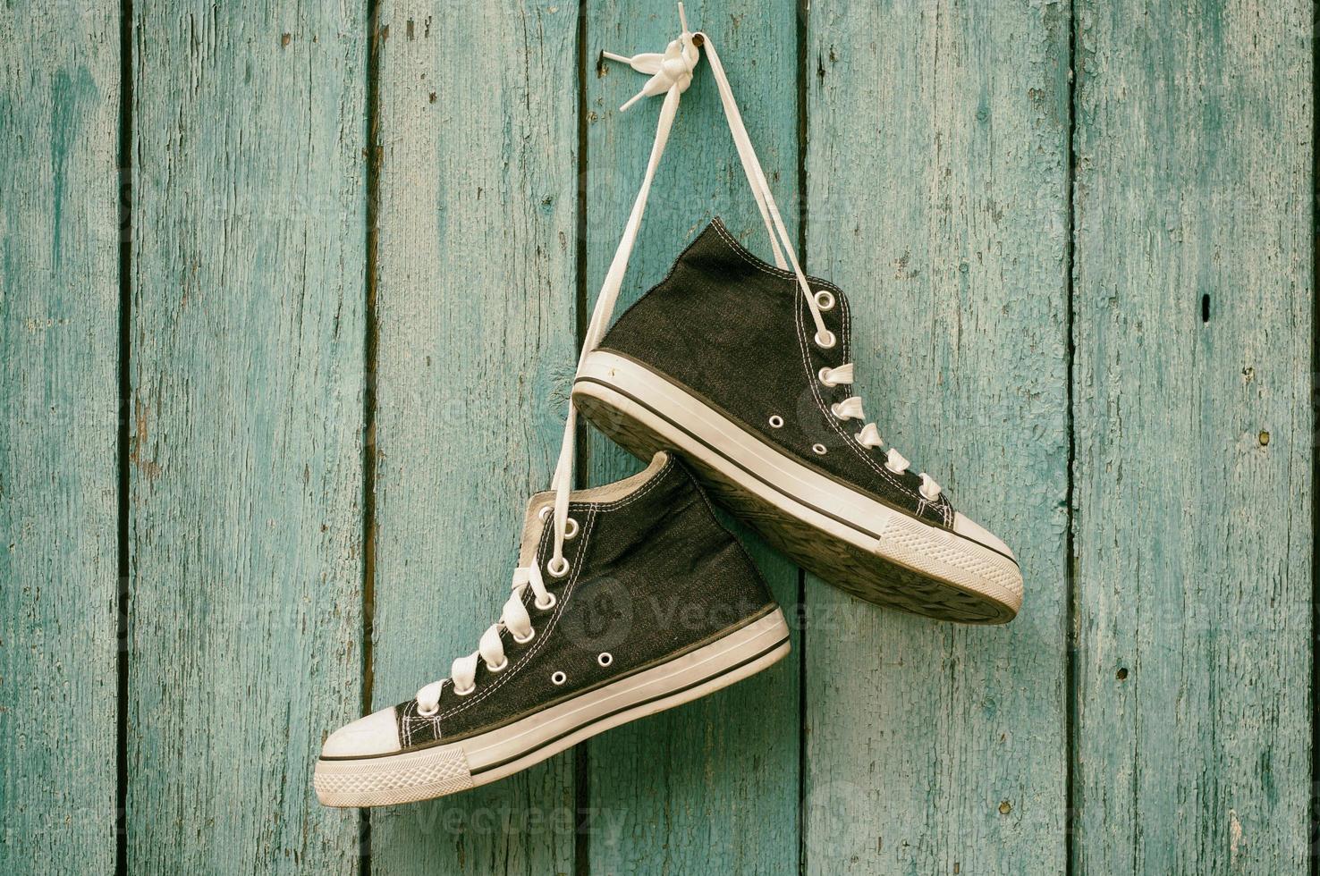 Blue sneakers hang on a nail on a blue wooden wall photo