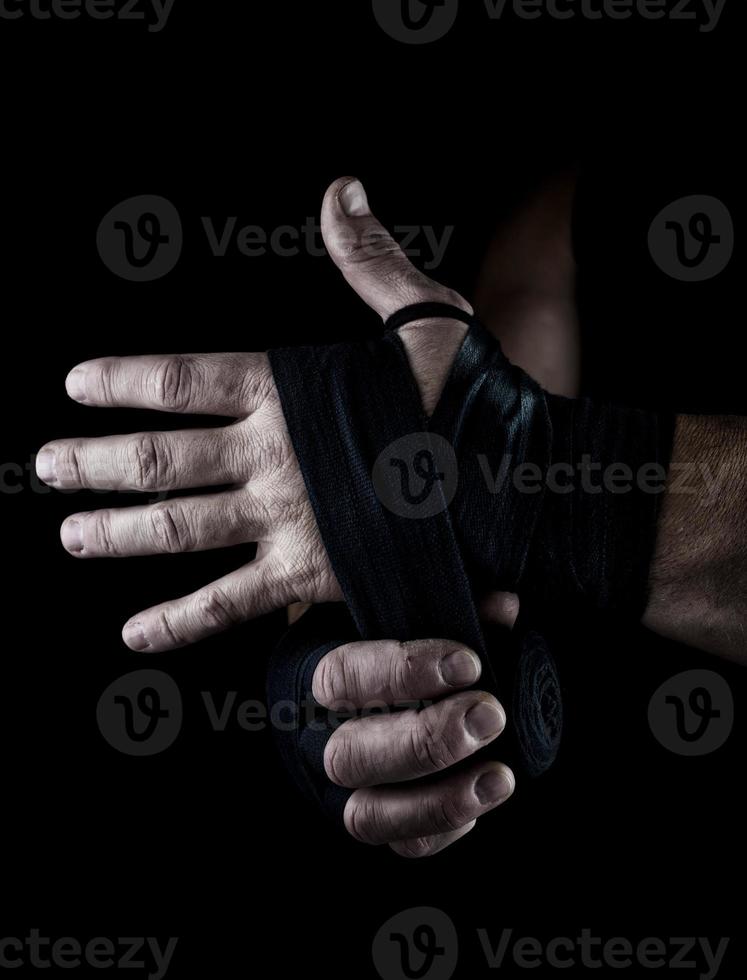 man wraps his hands in black textile bandage for sports photo