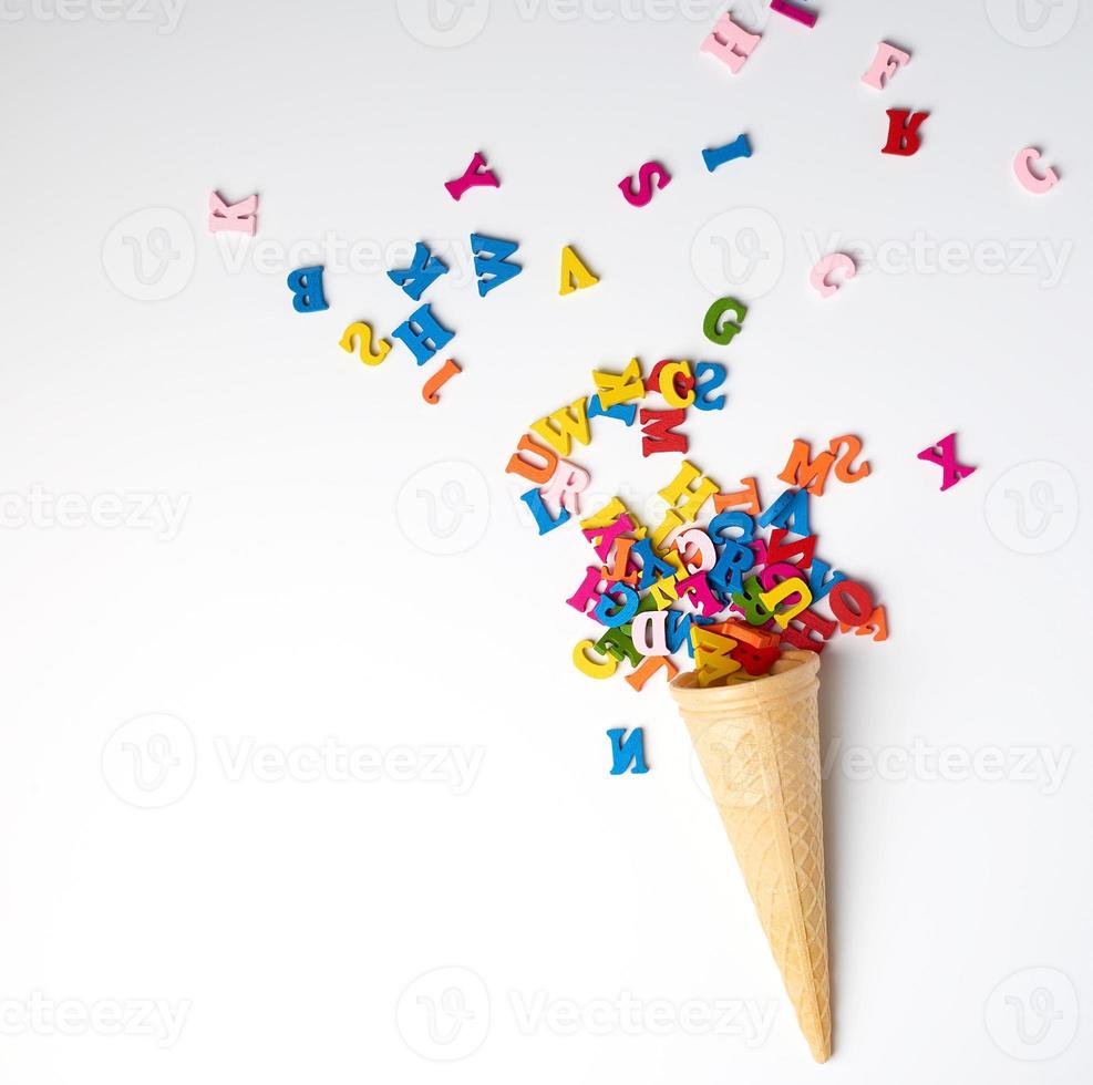 small wooden multi-colored letters of the English alphabet scattered from a conical waffle cup photo