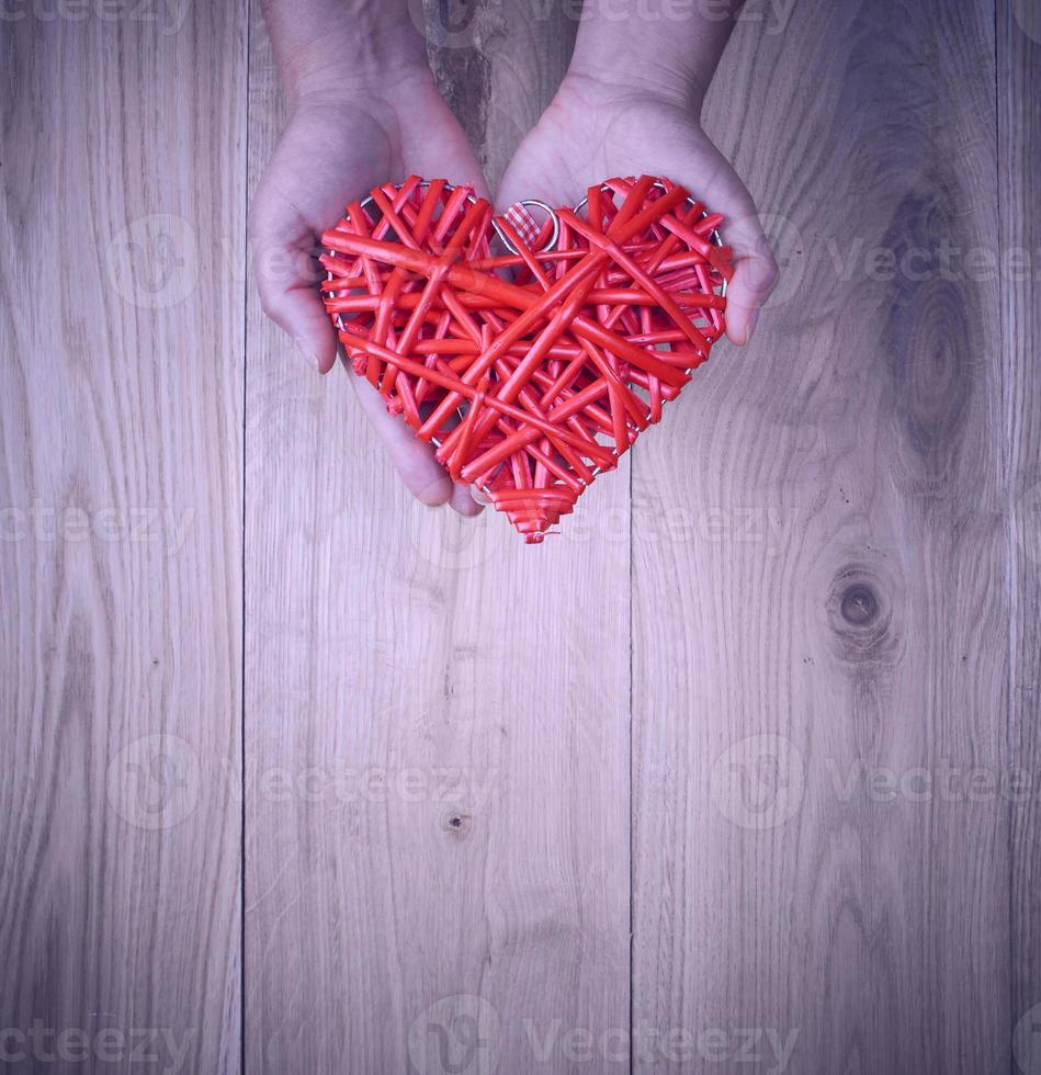 red heart in human hand on yellow wooden background photo