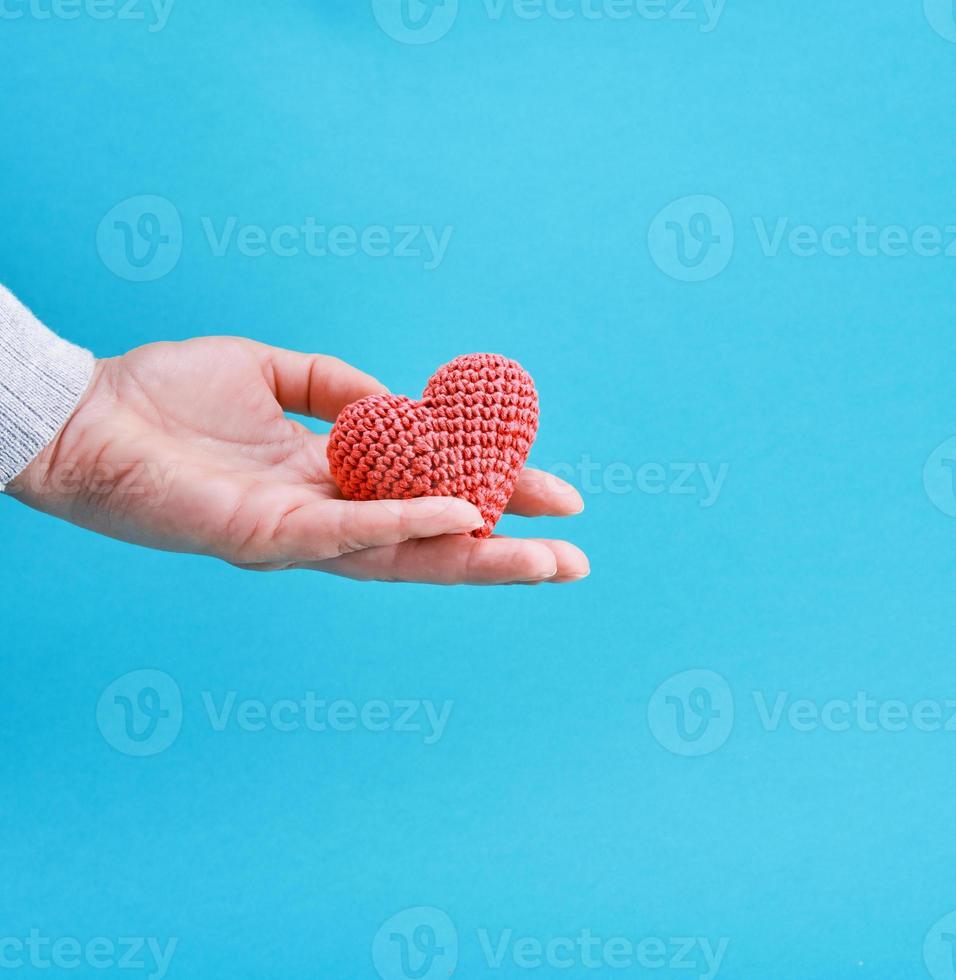 a small knitted red heart in a human hand photo