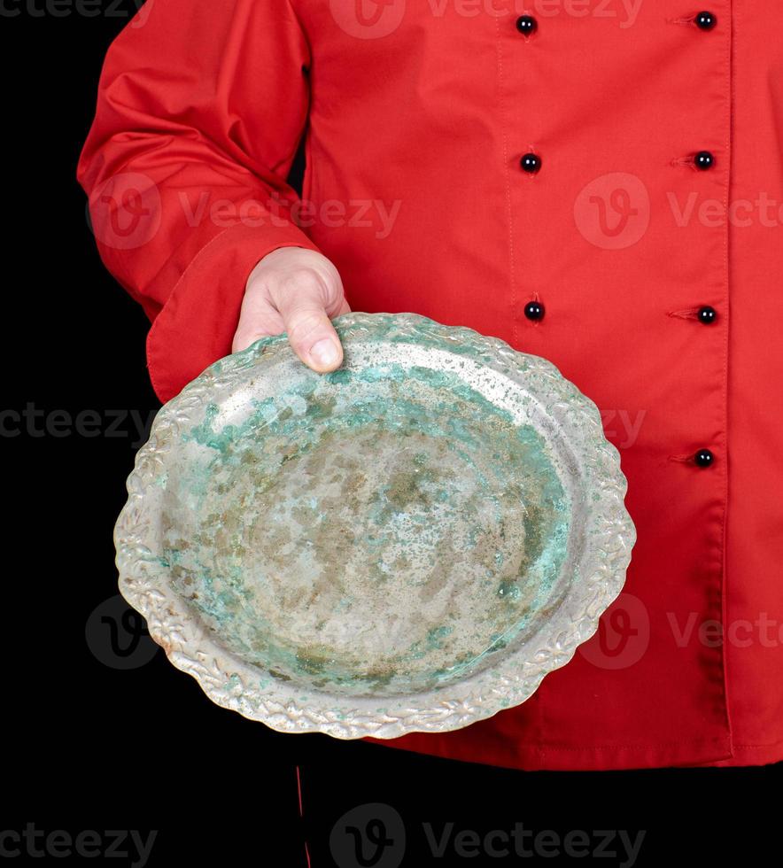 chef in red uniform holds in his hand an empty iron round dish photo