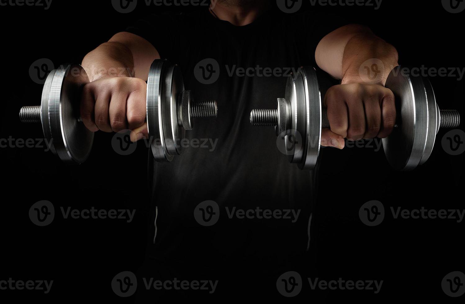 two steel typesetting dumbbells in male hands, sports backdrop photo